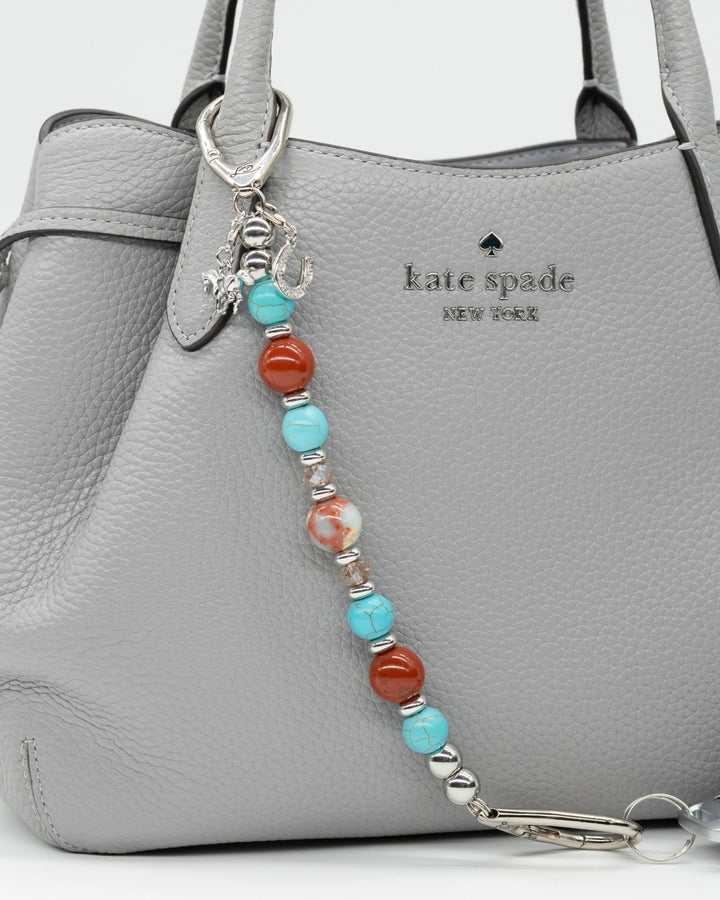 LD Keyfinder Cowgirl Dreams beaded bag charm with turquoise, red jasper, and imperial jasper on a grey leather handbag.