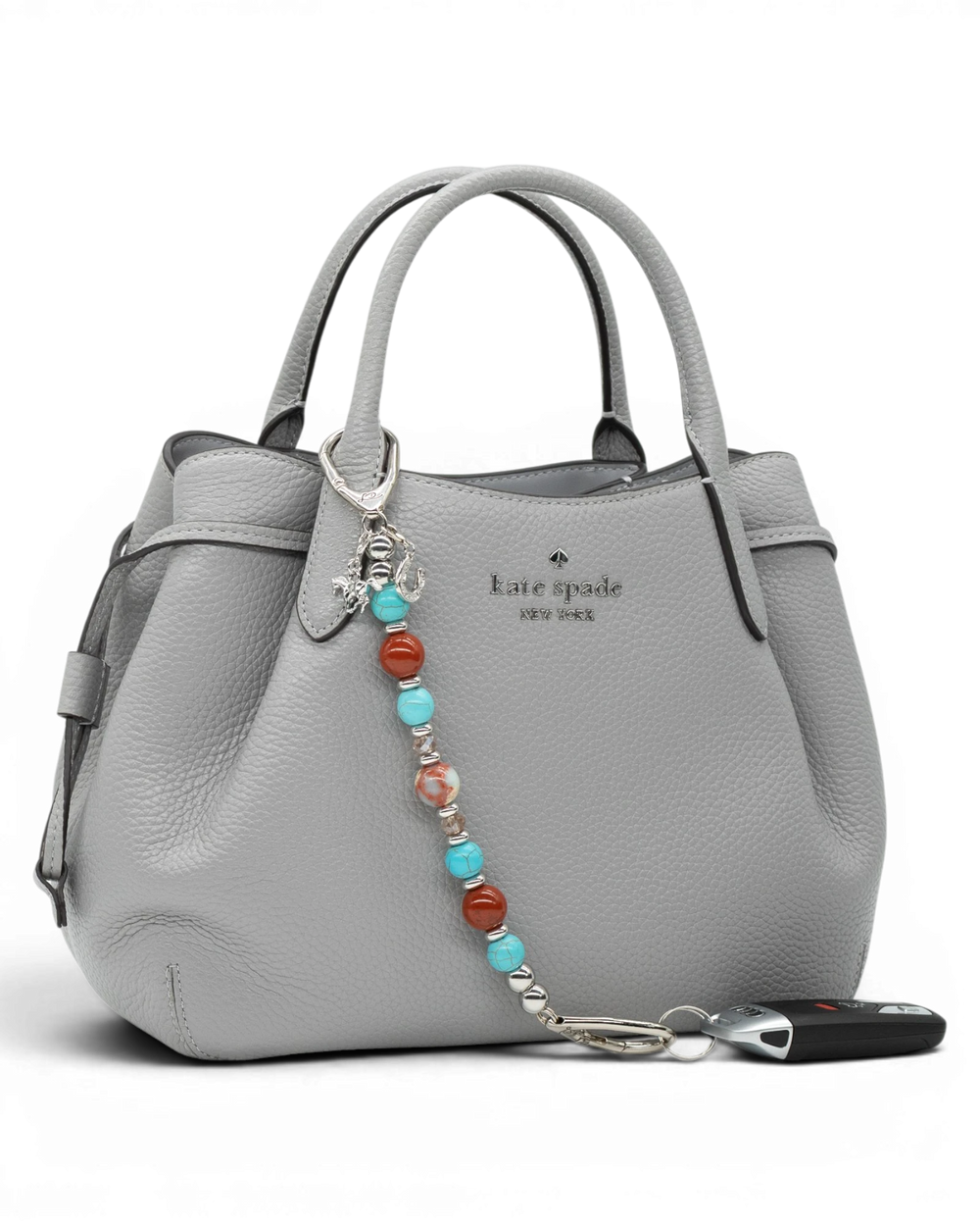 LD Keyfinder Cowgirl Dreams beaded keychain with turquoise, red jasper, and charms attached to a grey leather handbag.