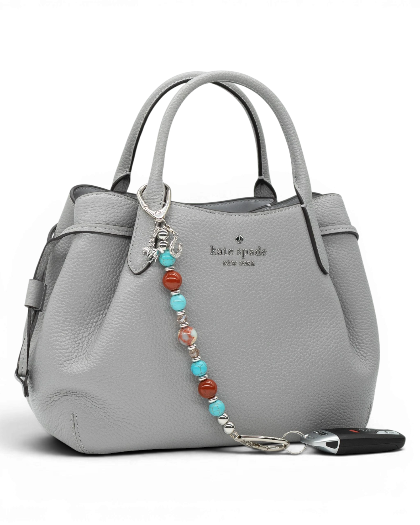 LD Keyfinder Cowgirl Dreams beaded keychain with turquoise, red jasper, and charms attached to a grey leather handbag.