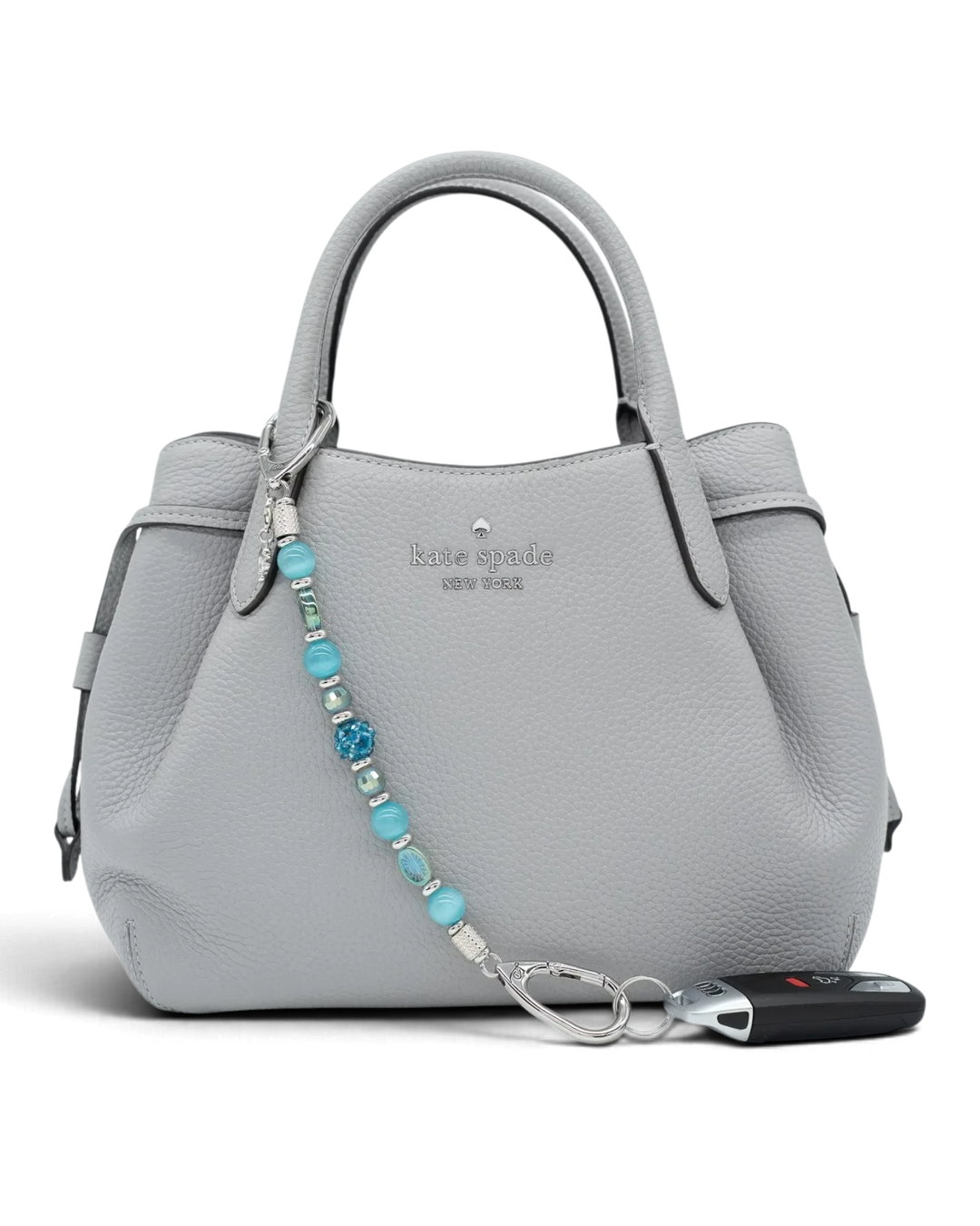 LD Keyfinder Dolphin Dream beaded accessory with aqua glass beads and a rhinestone dolphin charm on a grey handbag.