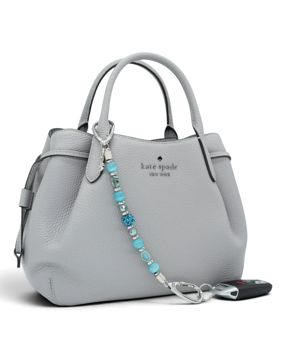 LD Keyfinder Dolphin Dream beaded key chain with aqua glass beads and a rhinestone dolphin charm on a grey handbag.