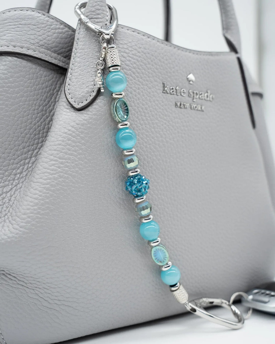 LD Keyfinder Dolphin Dream beaded purse charm with aqua glass beads and a rhinestone dolphin attached to a grey bag.