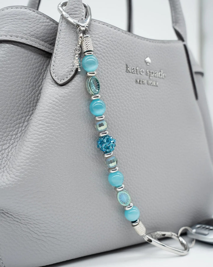 LD Keyfinder Dolphin Dream beaded purse charm with aqua glass beads and a rhinestone dolphin attached to a grey bag.