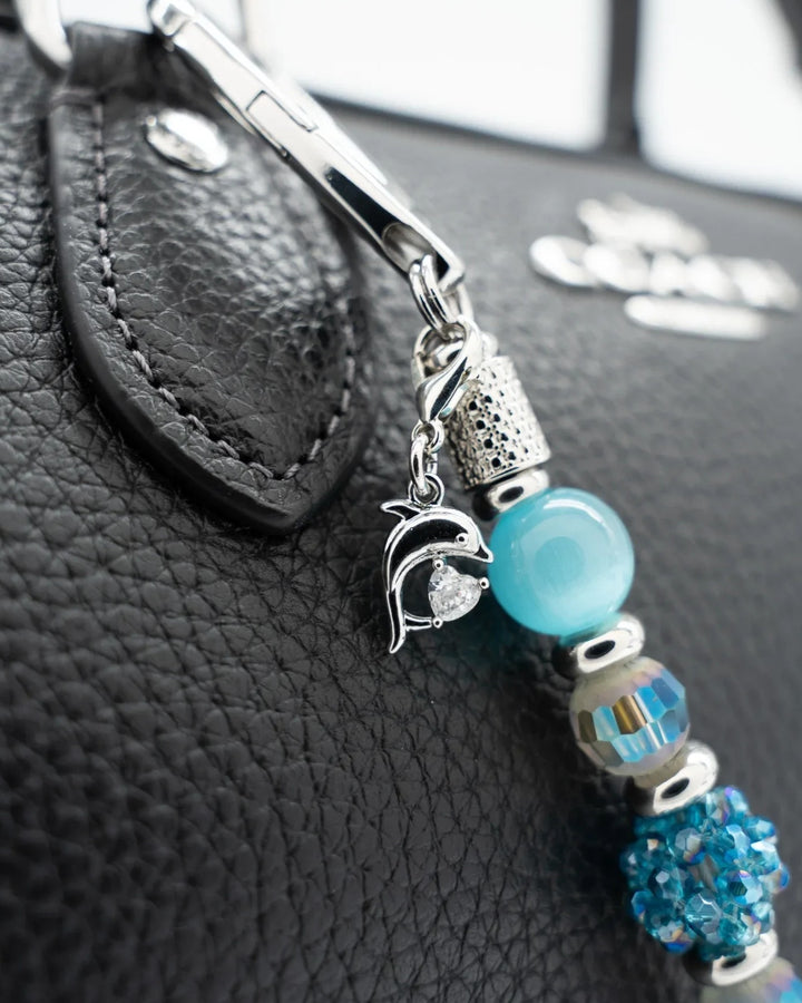 LD Keyfinder Dolphin Dream Mini featuring aqua cat's eye beads and a rhinestone dolphin charm attached to a black bag.
