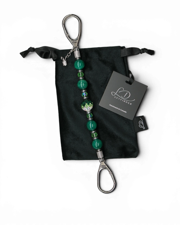 LD Keyfinder Emerald Links beaded keychain with green agate, Austrian crystal, and a golf bag charm on a velvet bag.