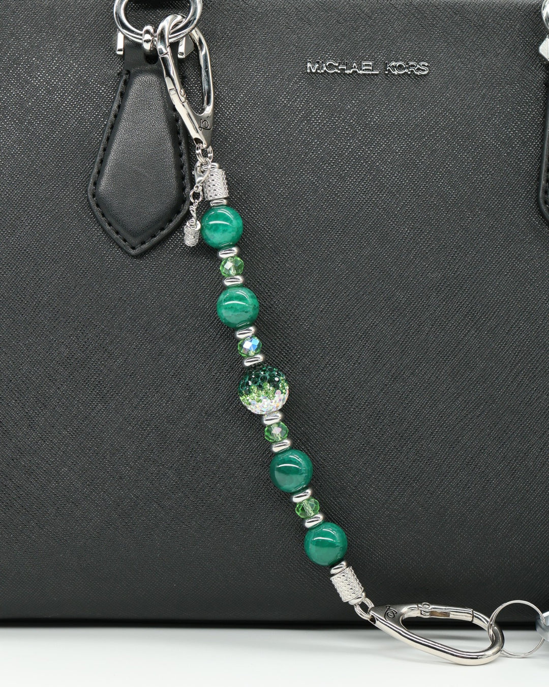 LD Keyfinder Emerald Links beaded keychain with green agate, glass beads, and a golf bag charm on a black handbag.