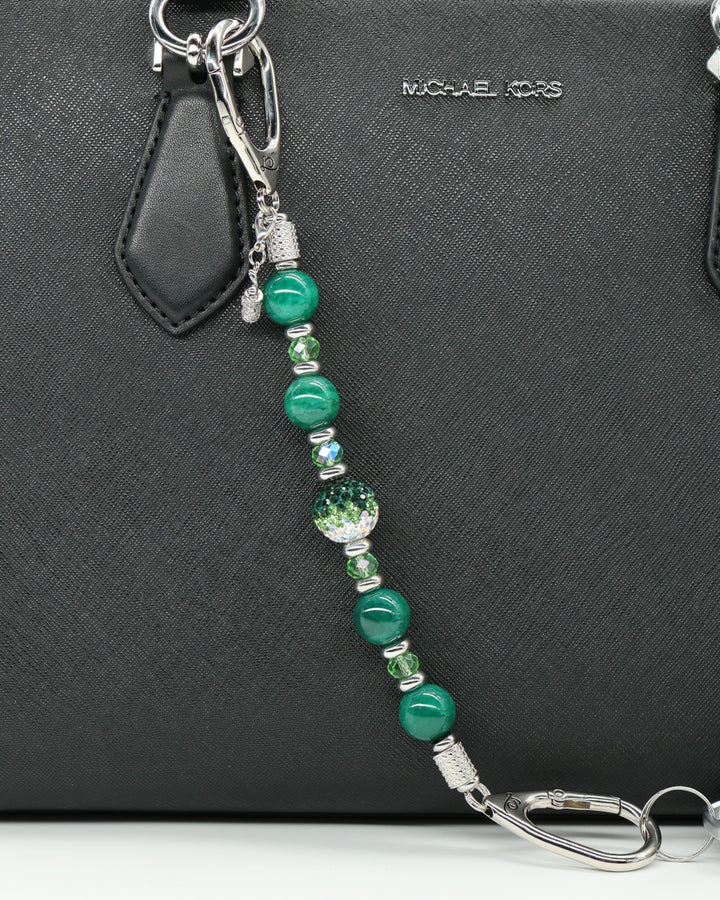 LD Keyfinder Emerald Links beaded keychain with green agate, glass beads, and a golf bag charm on a black handbag.