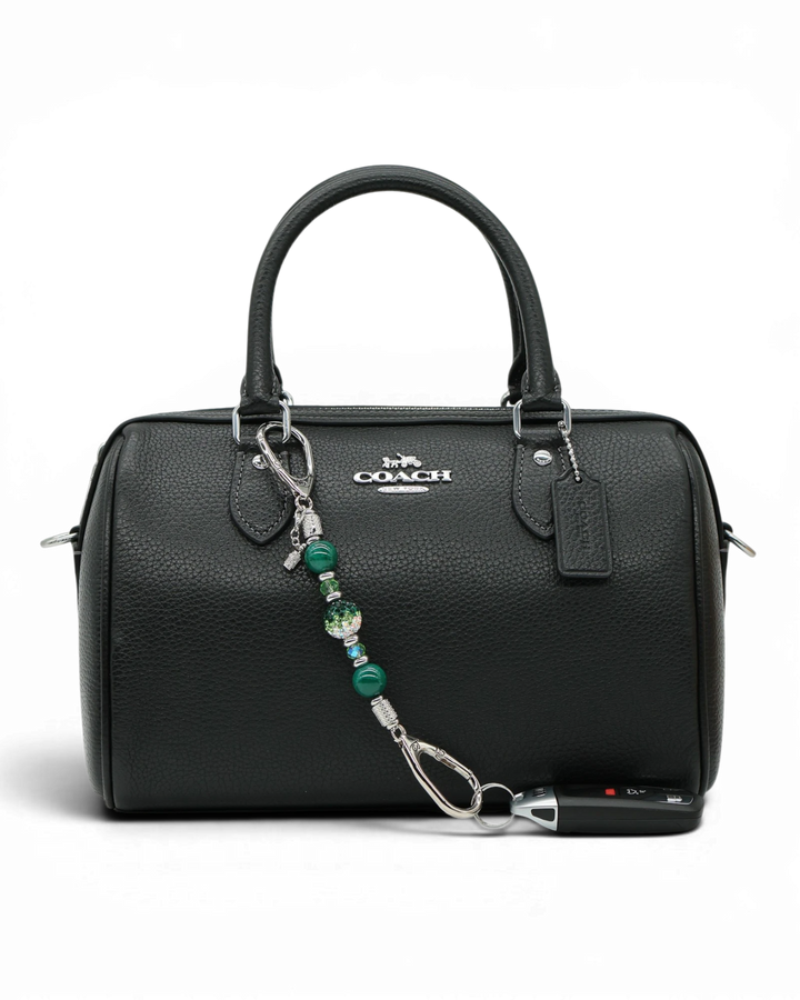LD Keyfinder Emerald Links Mini with green beads and golf bag charm attached to a black leather handbag