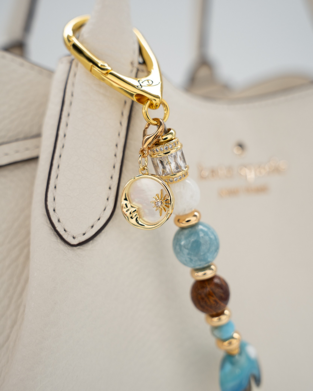 LD Keyfinder Equinox Harmony featuring moonstone, larimar, and jasper beads with a gold moon charm on a white handbag