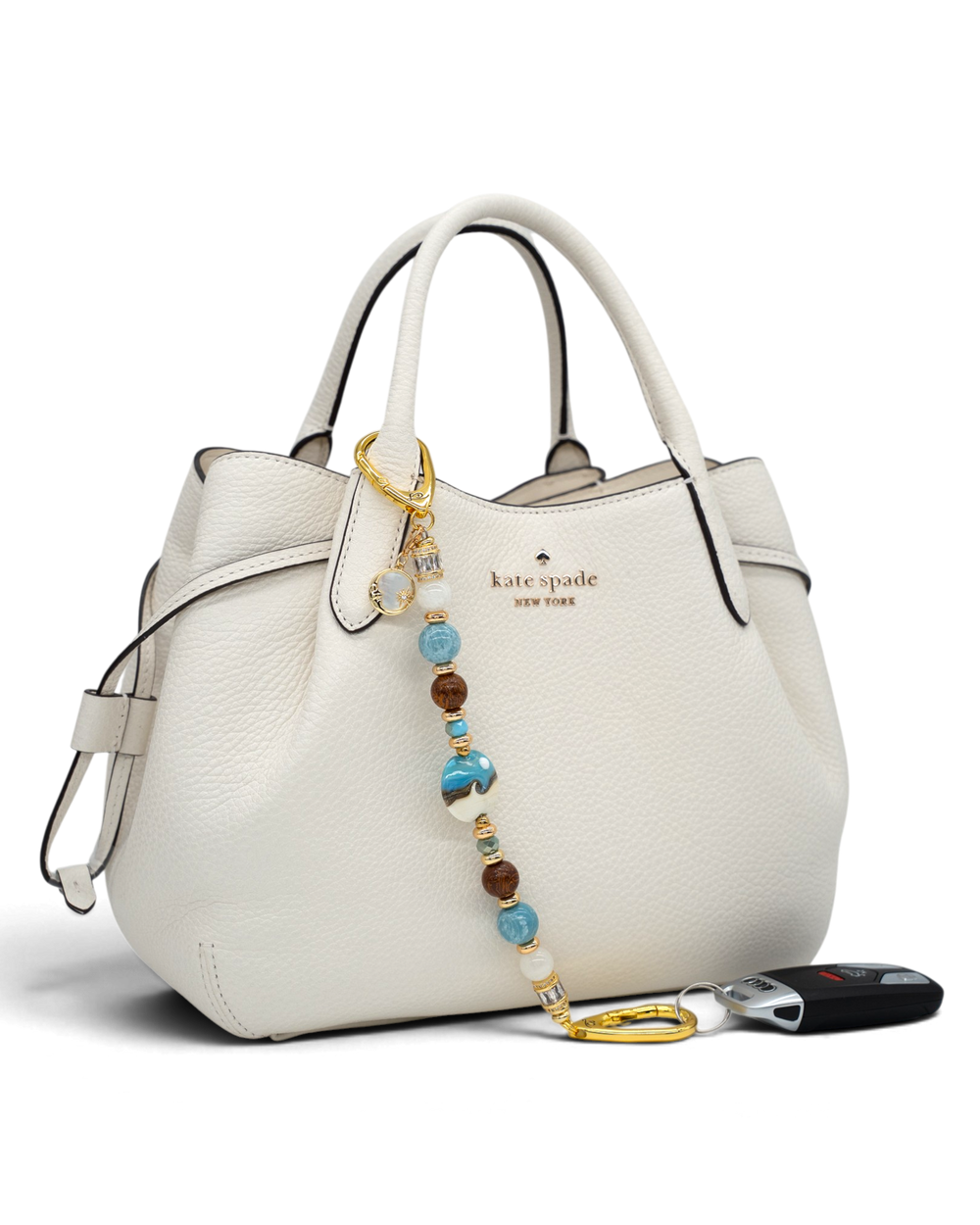 LD Keyfinder Equinox Harmony beaded accessory with moonstone, larimar, and glass moon charm attached to a white handbag
