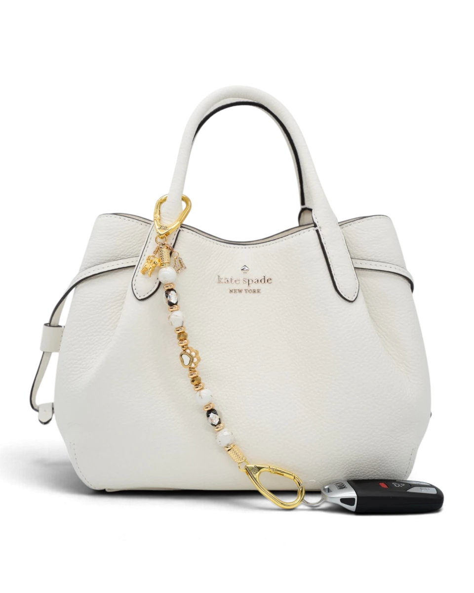 LD Keyfinder Furever Love beaded key chain with gold paw charm and white seashell beads attached to a white handbag.
