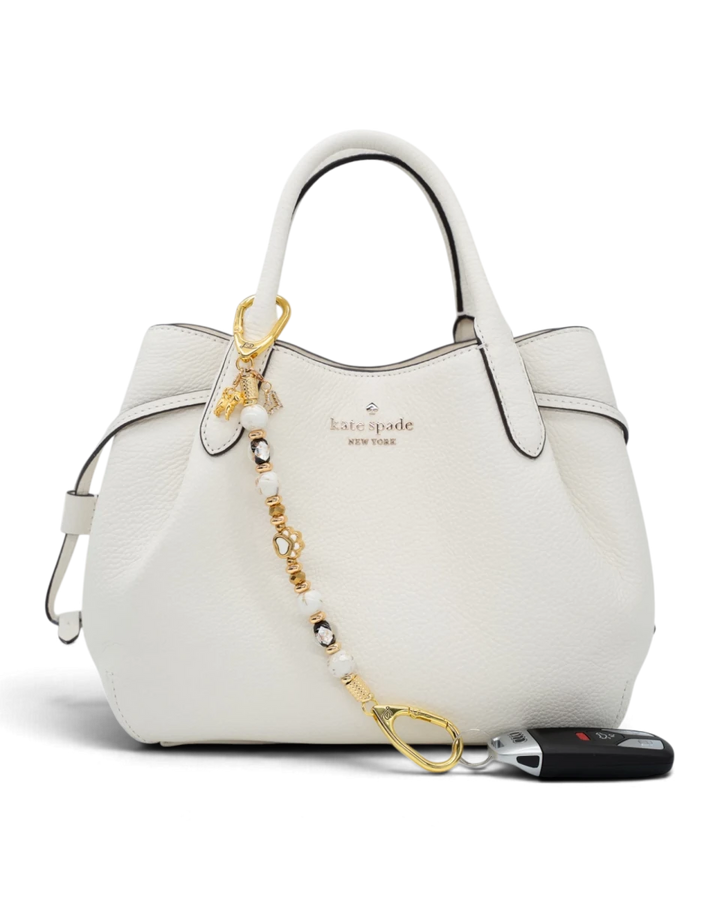 LD Keyfinder Furever Love beaded key chain with gold paw charm and white seashell beads attached to a white handbag.