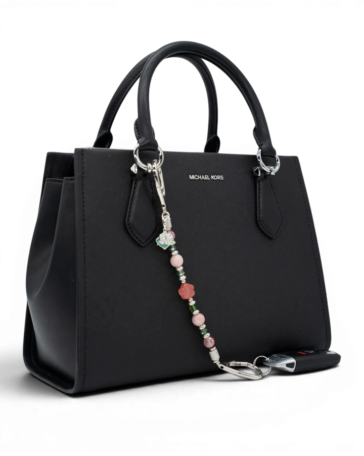 LD Keyfinder Garden Bliss beaded keychain with cherry quartz and pink opal attached to a black Michael Kors handbag.