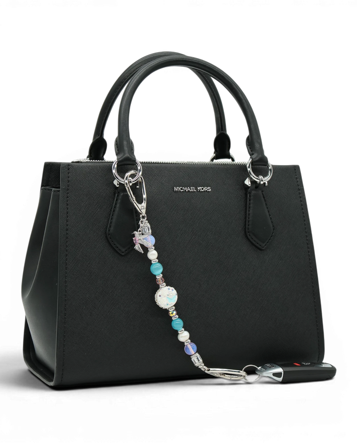 LD Keyfinder Garden Serenade beaded accessory with pearls, opalite, and hummingbird charm attached to a black handbag.