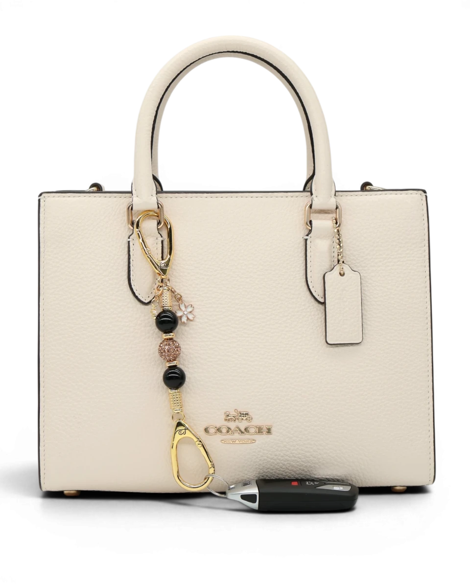LD Keyfinder Gilded Bee Mini keychain with black obsidian beads, crystal accents, and flower & bee charms on a cream handbag.