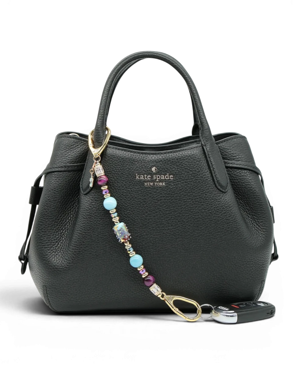 LD Keyfinder Gilded Fantasy beaded keychain with sky blue, topaz, purple, and gold accents, attached to a black handbag.