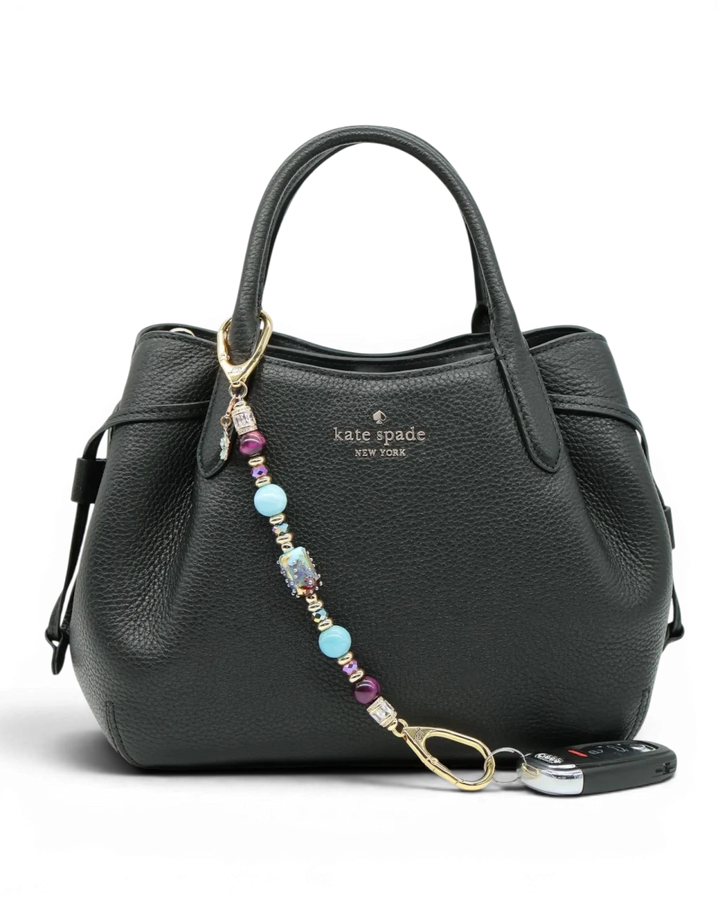LD Keyfinder Gilded Fantasy beaded keychain with sky blue, topaz, purple, and gold accents, attached to a black handbag.