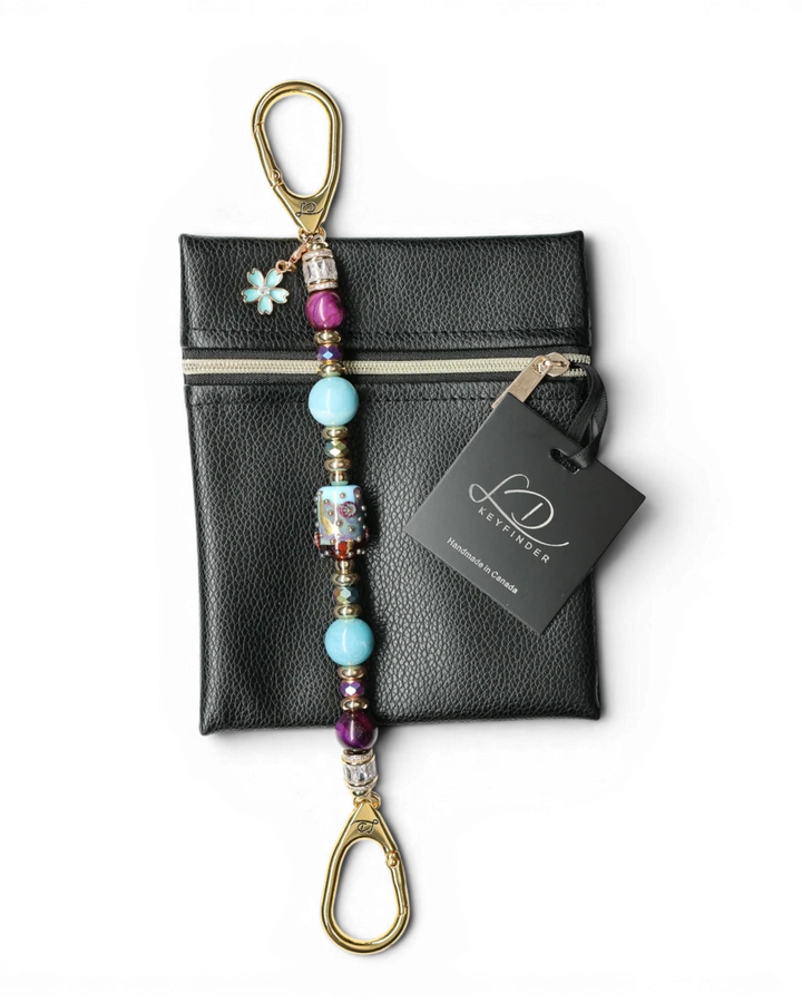 LD Keyfinder Gilded Fantasy keychain with sky blue, topaz, purple tiger eye beads, gold leaf art bead, and blue flower charm on black pouch.