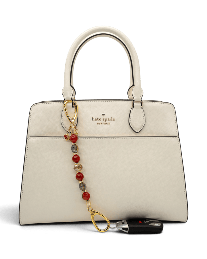 LD Keyfinder Golden Autumn beaded accessory with agate and crystal charms attached to a cream Kate Spade handbag