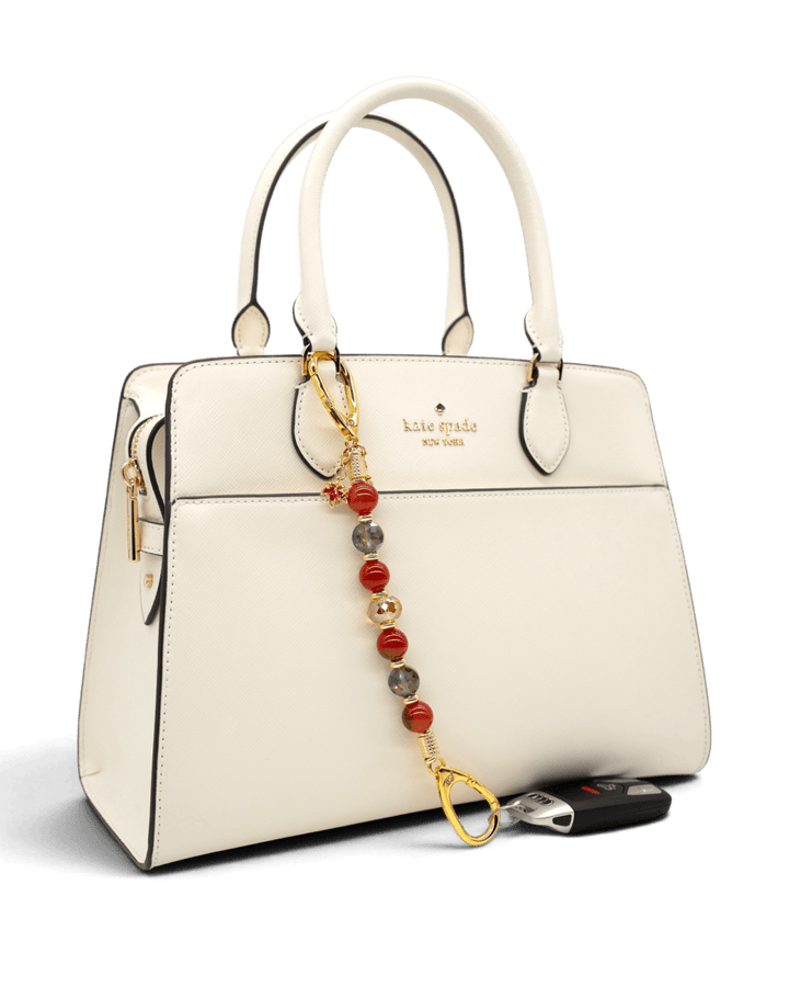 LD Keyfinder Golden Autumn beaded key finder with agate and crystal charms attached to a white handbag