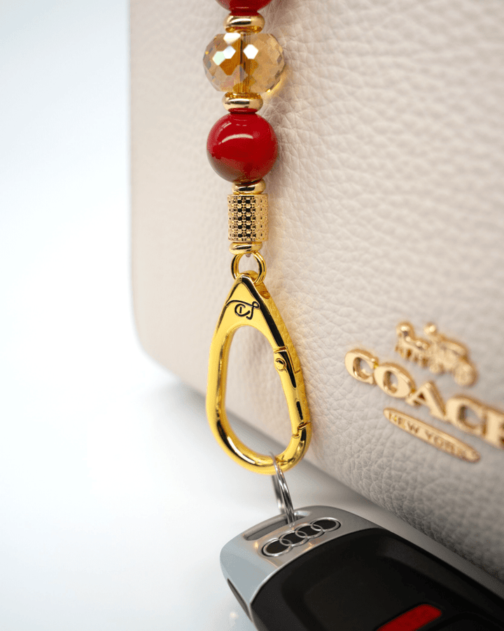 LD Keyfinder Golden Autumn Mini featuring red and amber beads, gold-plated accents, and charms attached to a handbag.