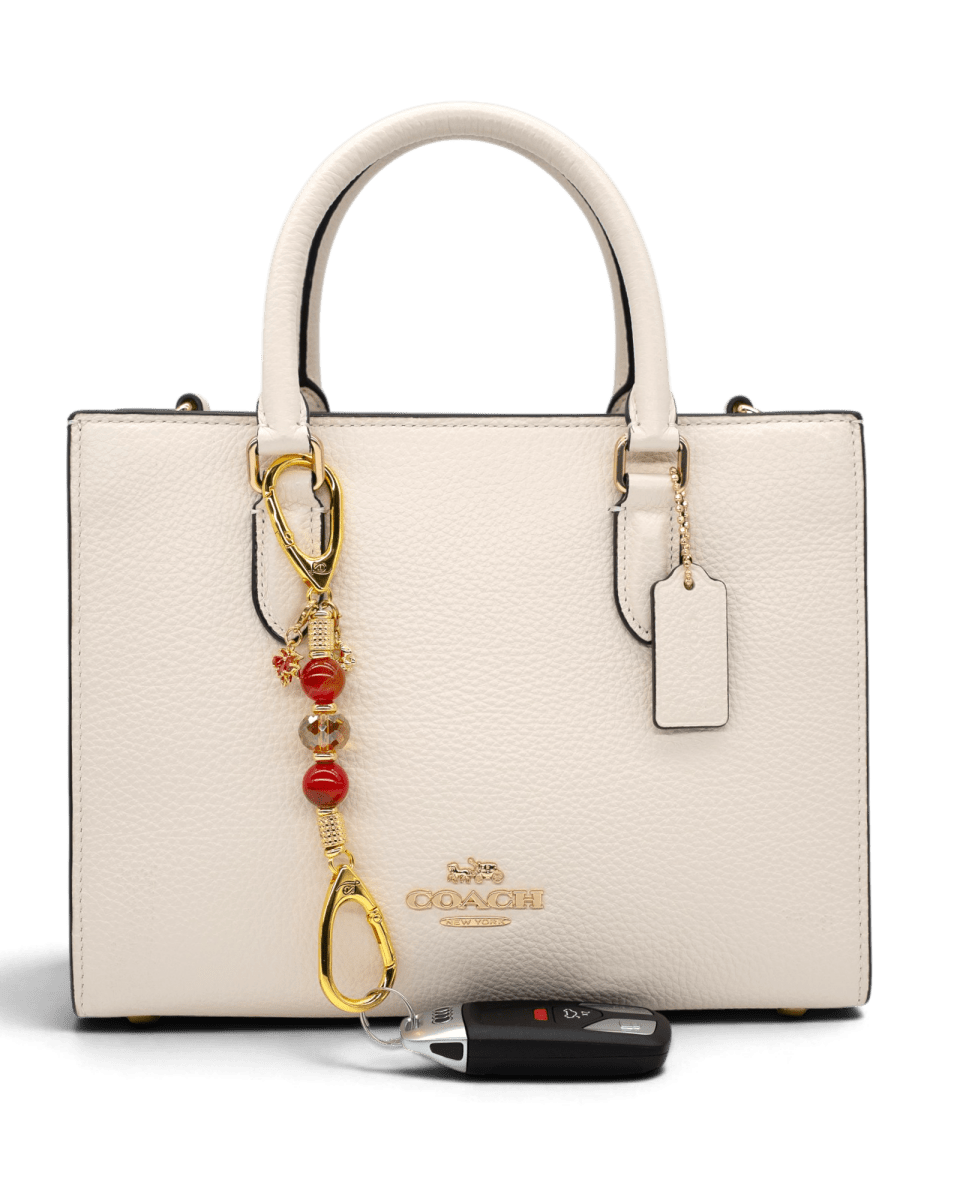 LD Keyfinder Golden Autumn-Mini charm with agate beads and gold squirrel charm attached to a cream Coach handbag