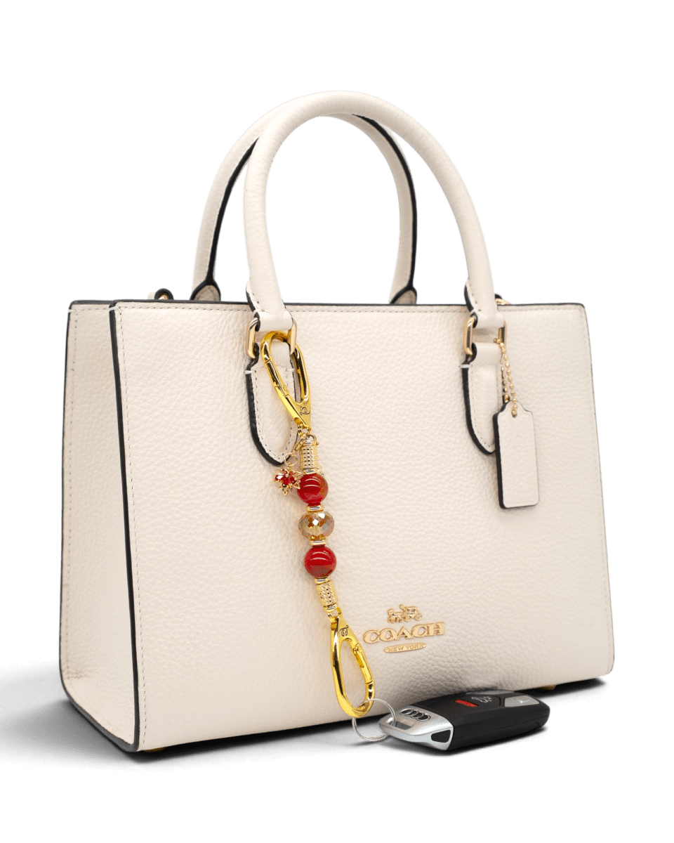 LD Keyfinder Golden Autumn-Mini featuring agate beads, amber crystal, and gold charms attached to a cream handbag.