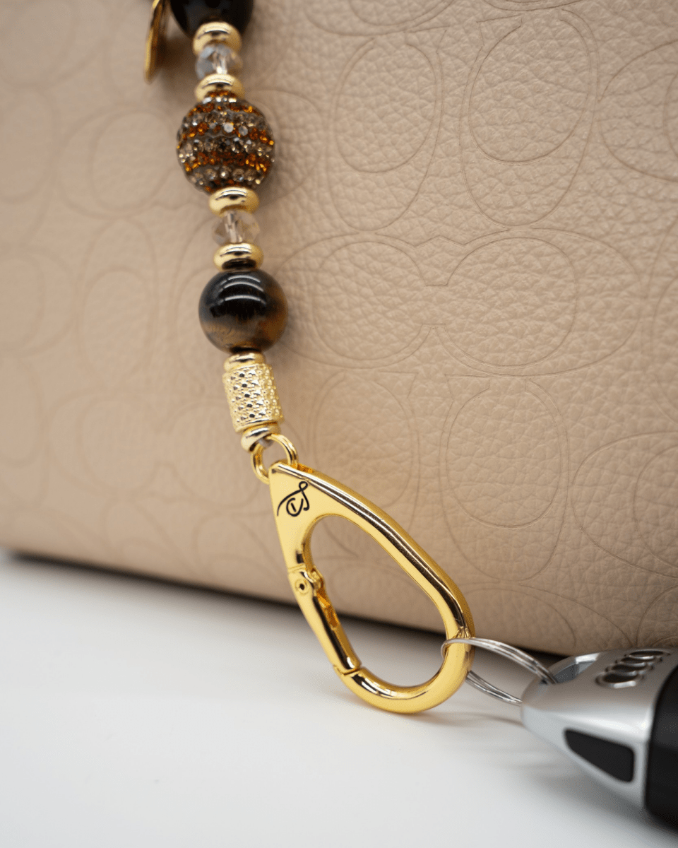 LD Keyfinder Golden Equinox-Mini featuring Tiger Eye beads, gold-plated accents, and a sun and moon charm on a bag