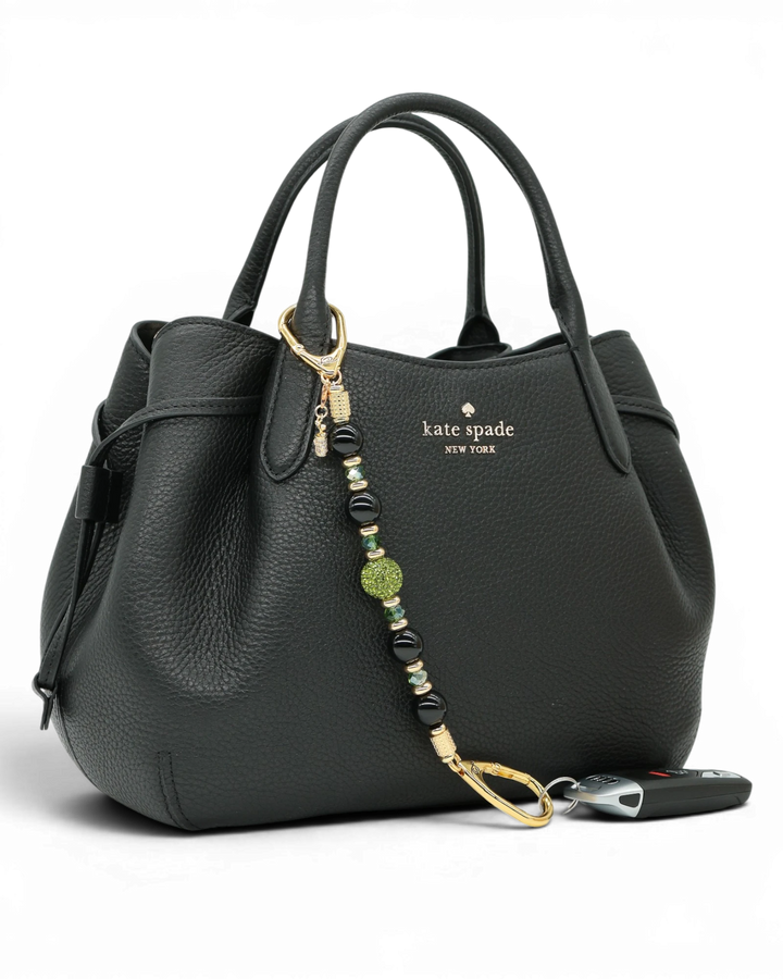 LD Keyfinder Golden Fairway beaded keychain with obsidian, moss green crystals, and a golf bag charm on a black bag.