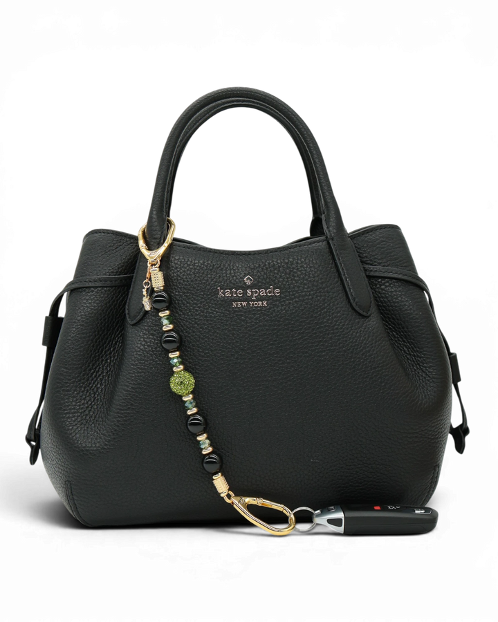 LD Keyfinder Golden Fairway beaded keychain with black obsidian, moss green crystal, and golf bag charm on a handbag.