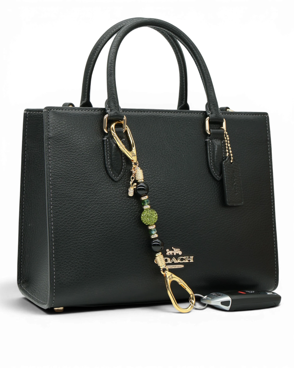 LD Keyfinder Golden Fairway Mini with obsidian, moss green crystals, and a golf bag charm attached to a black bag.