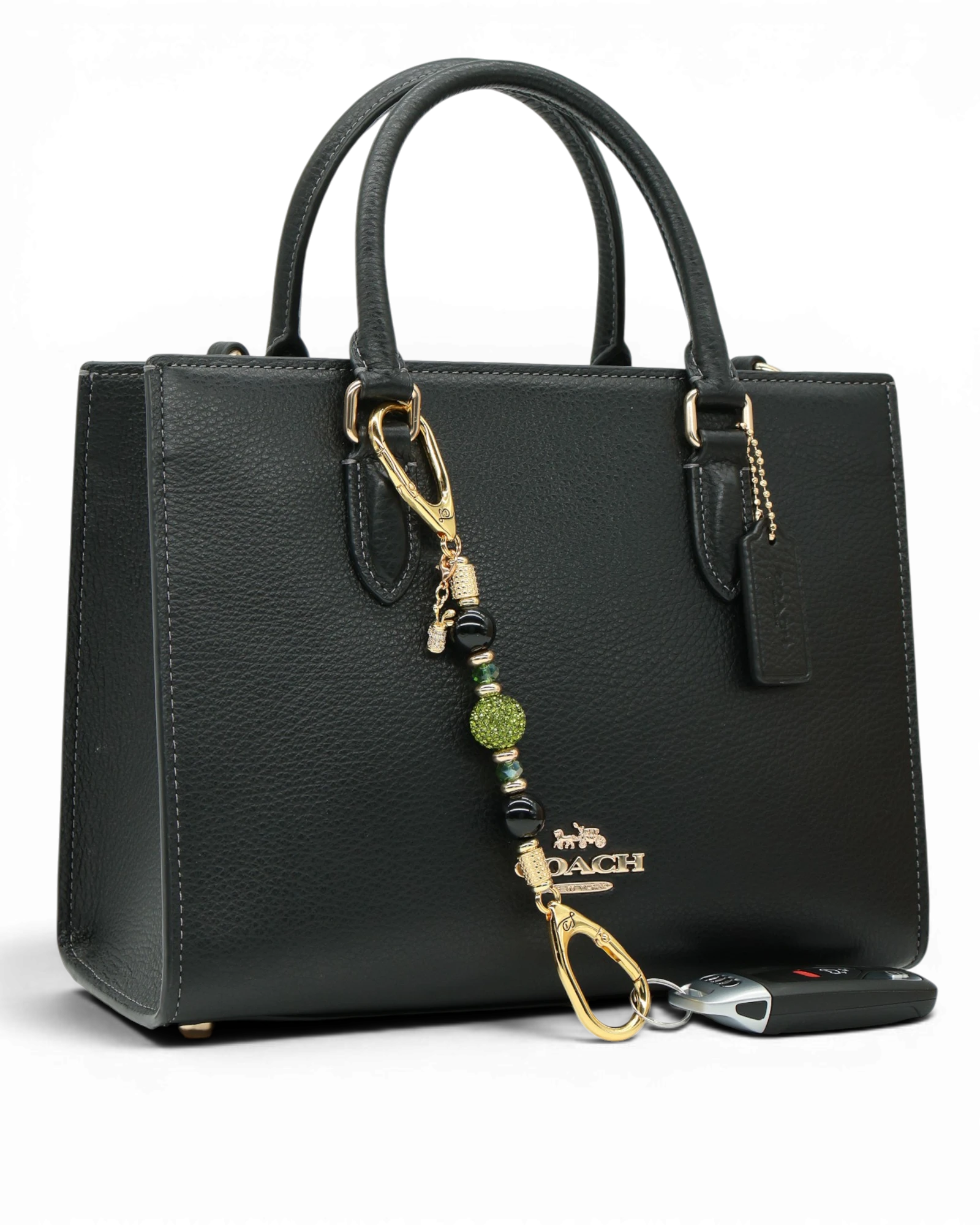 LD Keyfinder Golden Fairway Mini with obsidian, moss green crystals, and a golf bag charm attached to a black bag.