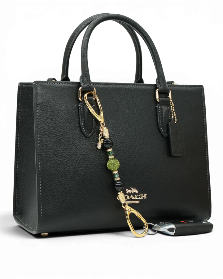 LD Keyfinder Golden Fairway Mini with obsidian, moss green crystals, and a golf bag charm attached to a black bag.