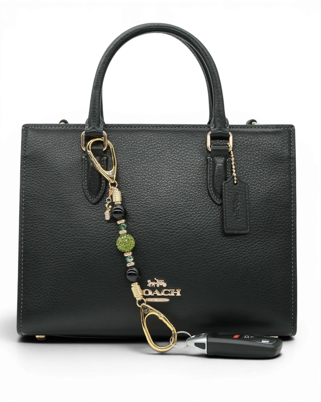 LD Keyfinder Golden Fairway Mini with obsidian, moss green crystal, and a rhinestone golf bag charm on a black bag.