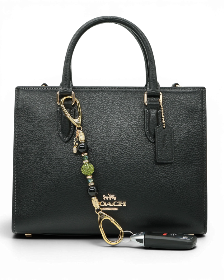 LD Keyfinder Golden Fairway Mini with obsidian, moss green crystal, and a rhinestone golf bag charm on a black bag.