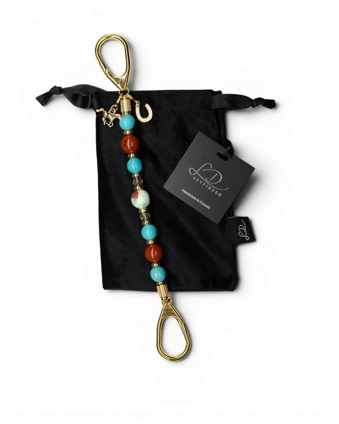 LD Keyfinder Golden Prairie beaded keychain with turquoise, red jasper, and gold charms on a black velvet pouch.