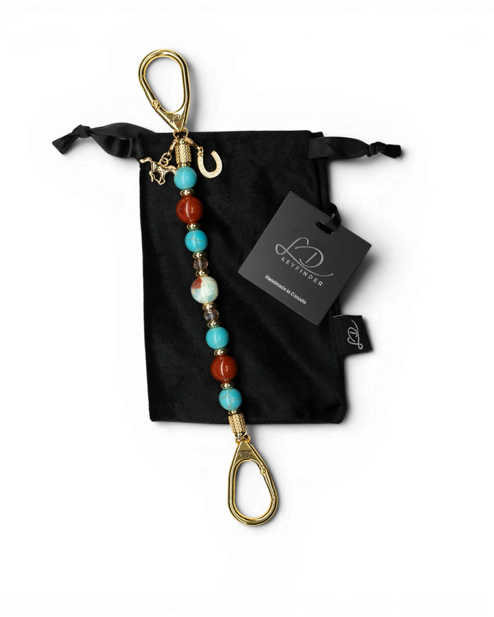LD Keyfinder Golden Prairie beaded keychain with turquoise, red jasper, and gold charms on a black velvet pouch.