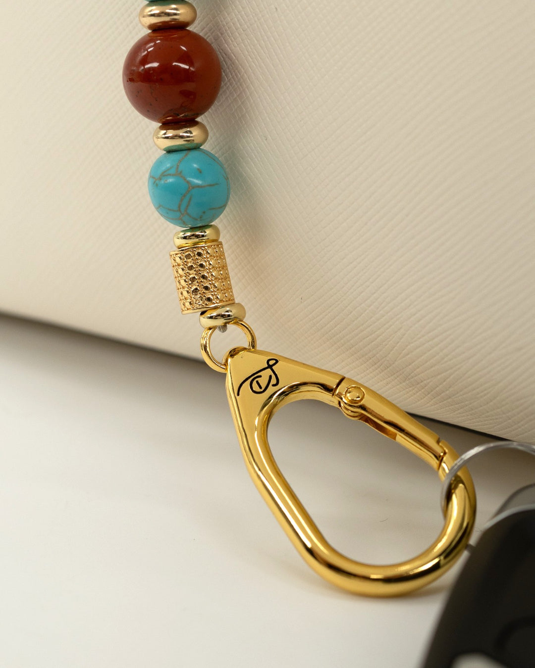 LD Keyfinder Golden Prairie beaded keychain with turquoise, red jasper, and 18KT gold-plated accents on a white bag
