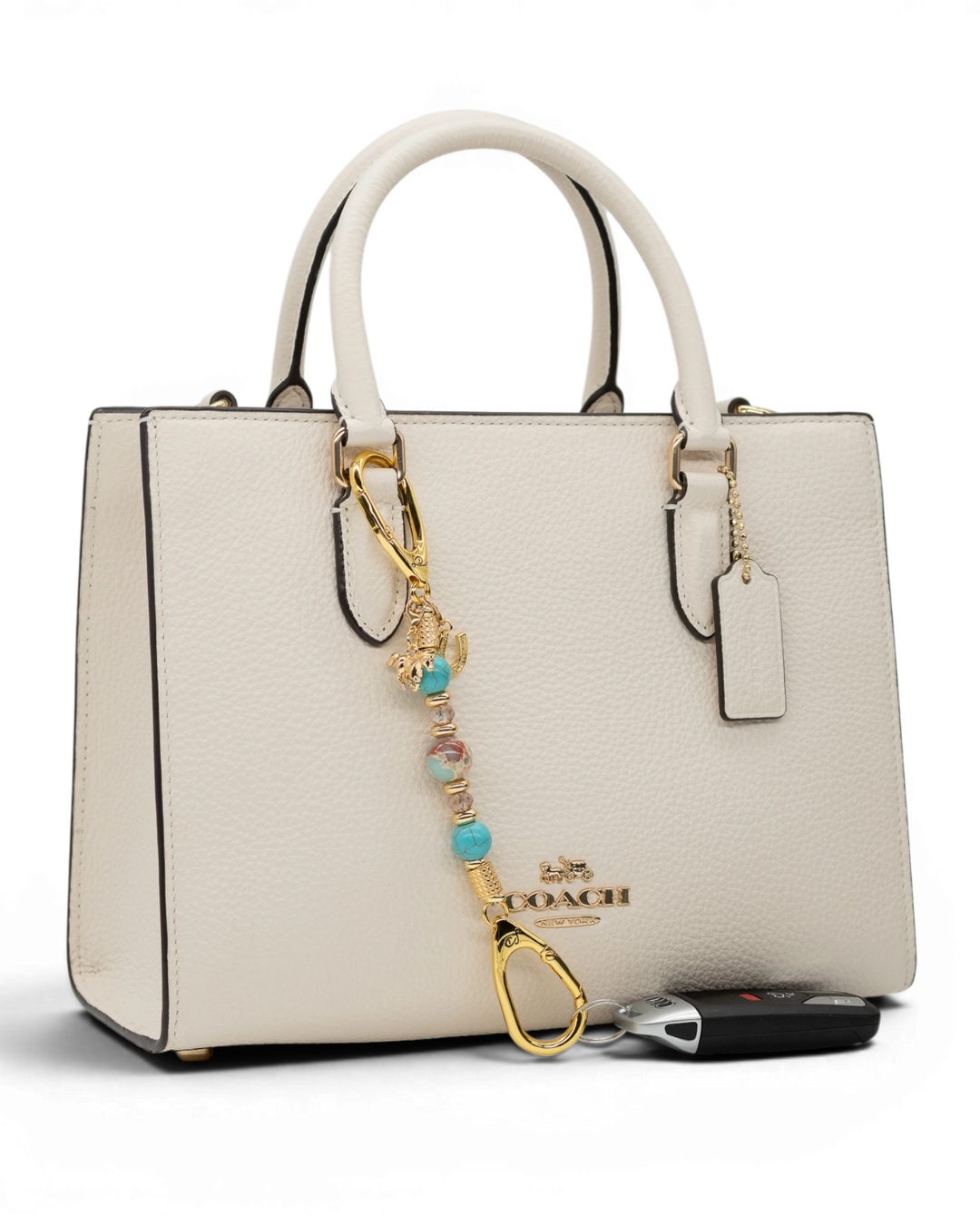 LD Keyfinder Golden Prairie-Mini beaded charm with turquoise and gold accents attached to a white leather handbag.