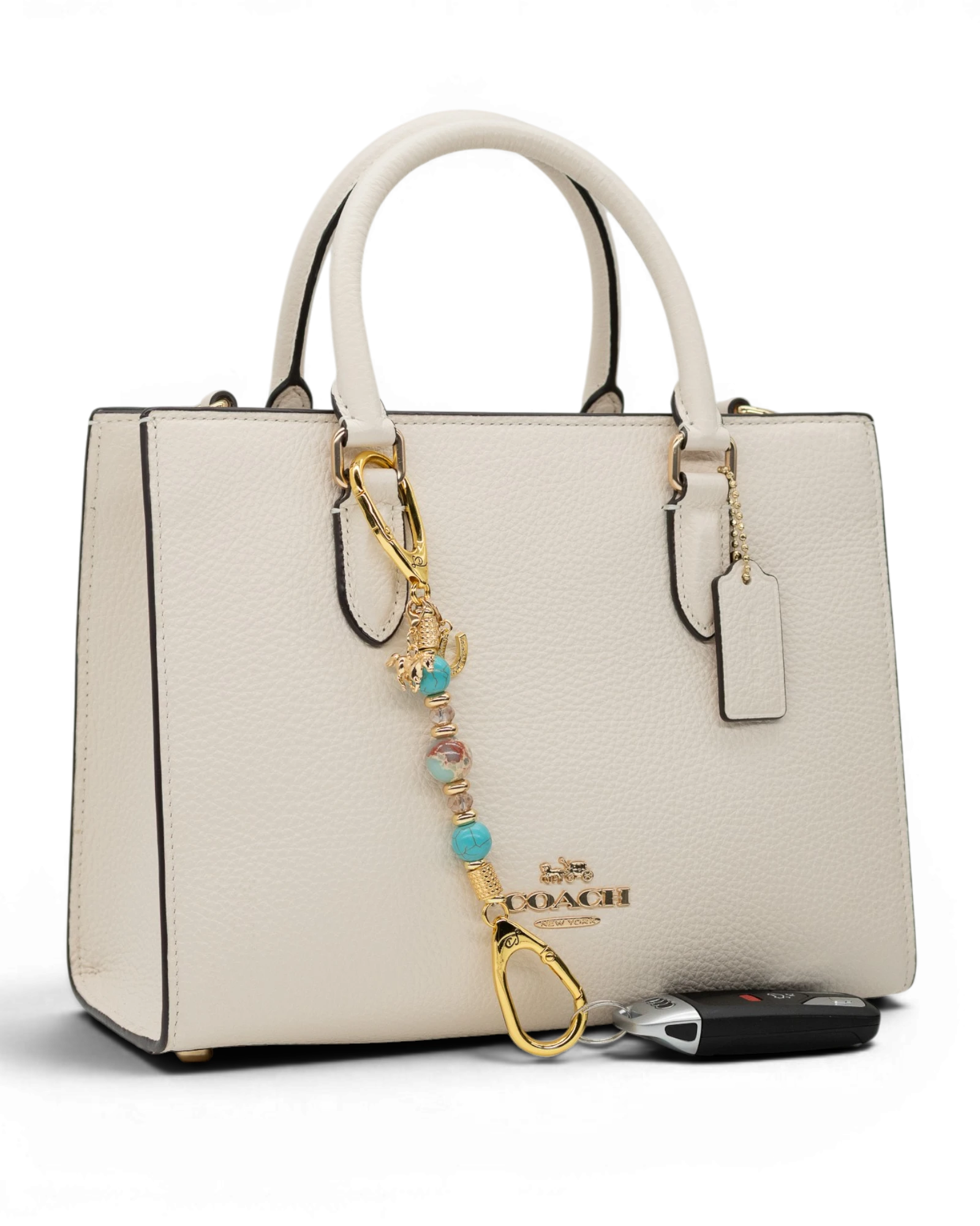 LD Keyfinder Golden Prairie-Mini beaded charm with turquoise and gold accents attached to a white leather handbag.