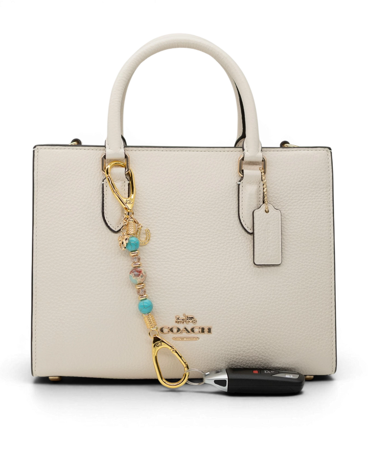 LD Keyfinder Golden Prairie-Mini beaded charm with turquoise and gold accents attached to a white leather handbag