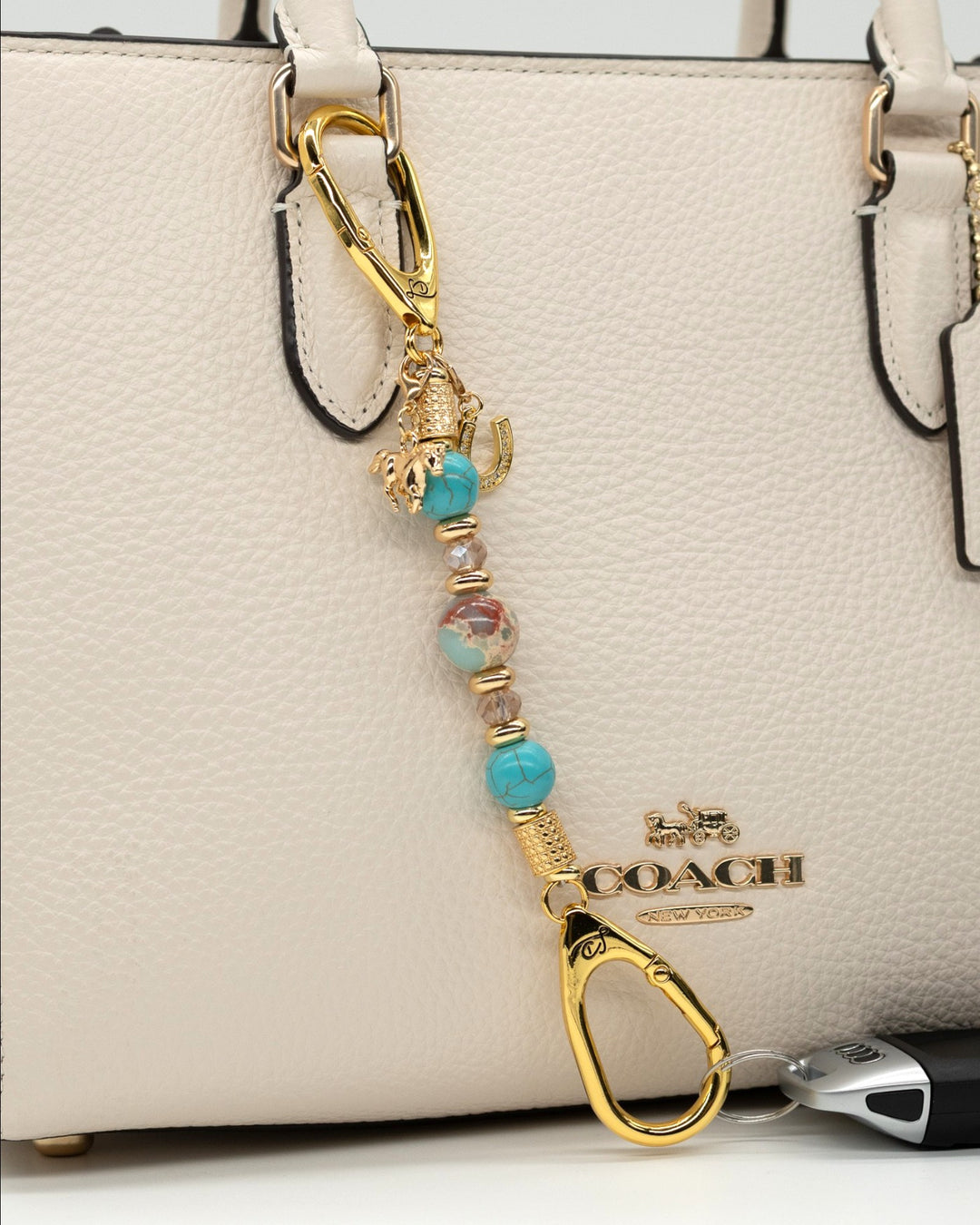 LD Keyfinder Golden Prairie-Mini beaded keychain with turquoise, jasper, and gold charms attached to a white handbag.