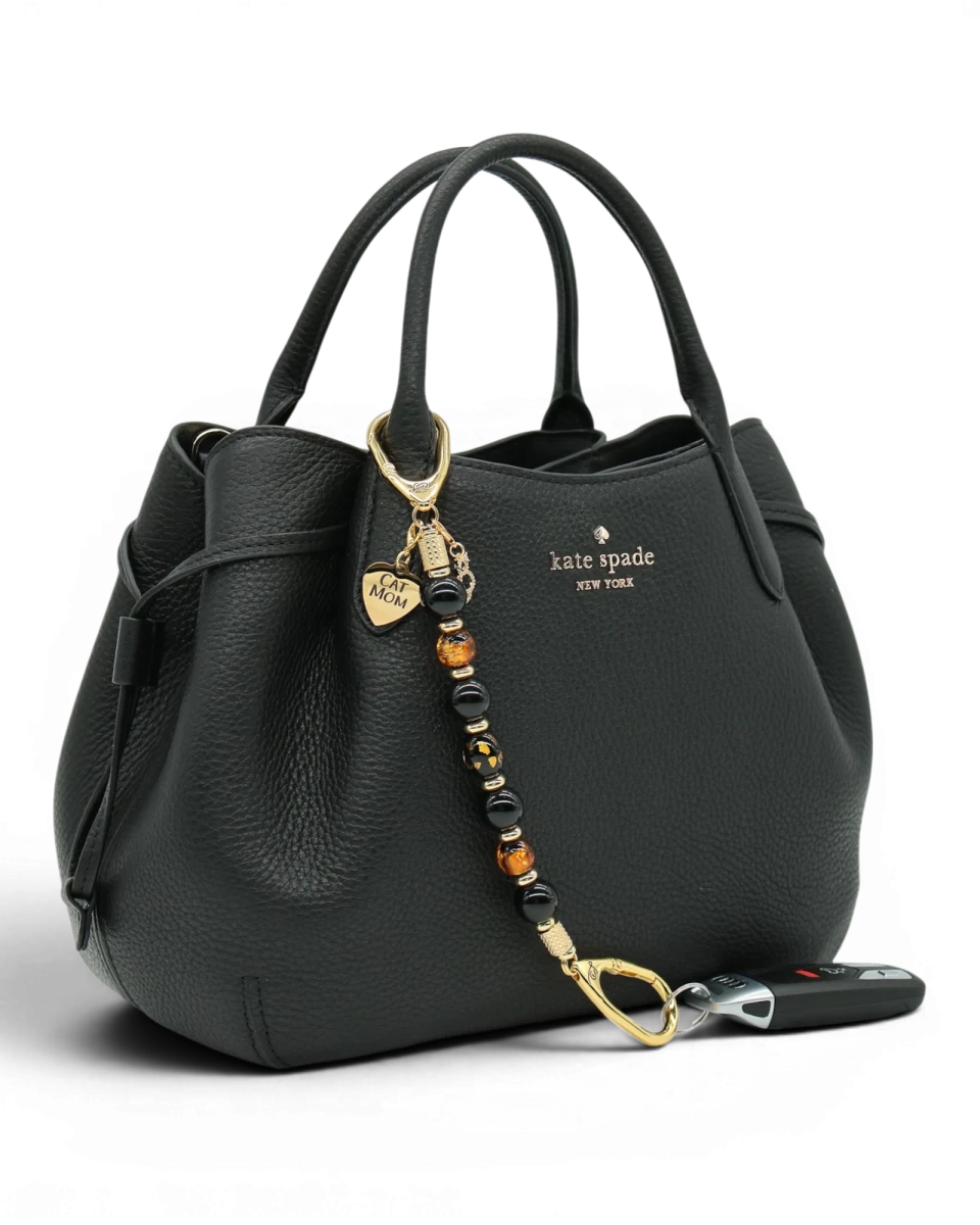 LD Keyfinder Golden Purrs beaded key chain with black obsidian and gold foil lampwork beads attached to a black handbag.