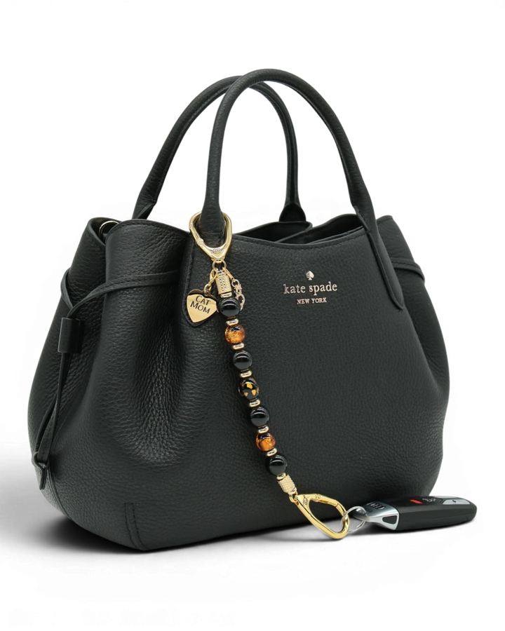 LD Keyfinder Golden Purrs beaded key chain with black obsidian and gold foil lampwork beads attached to a black handbag.