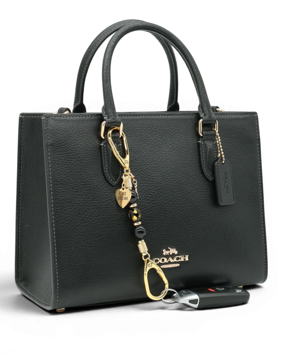 LD Keyfinder Golden Purrs-Mini accessory with black obsidian and gold cat charms attached to a black leather handbag.