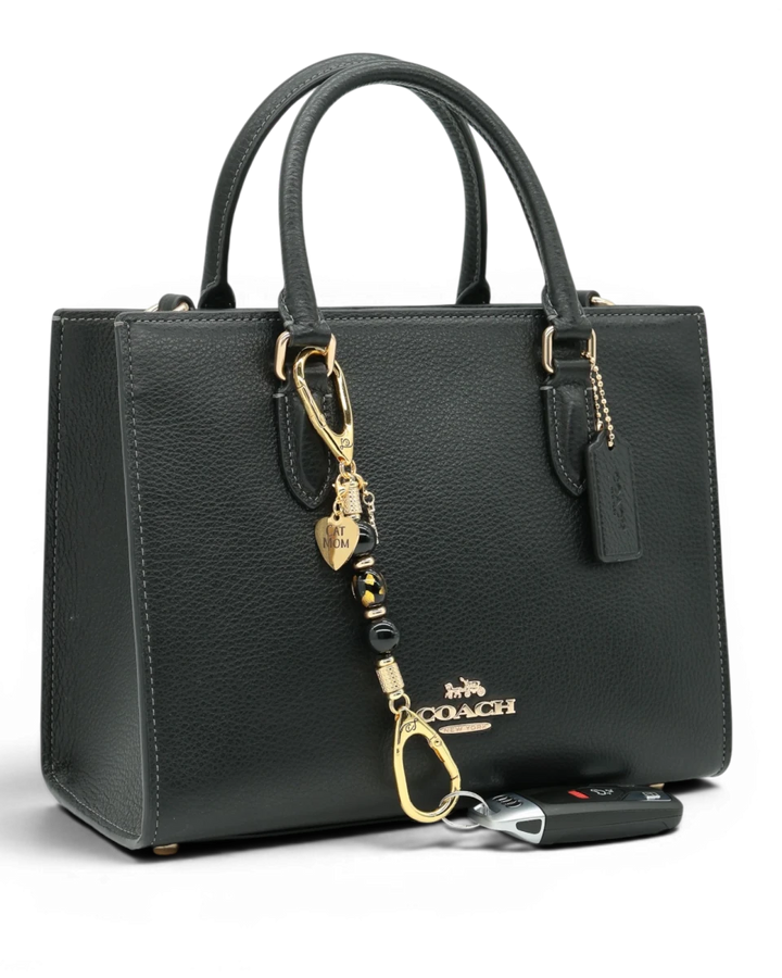 LD Keyfinder Golden Purrs-Mini accessory with black obsidian and gold cat charms attached to a black leather handbag.
