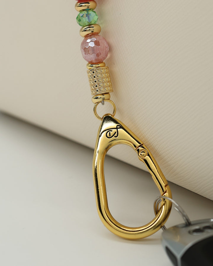 LD Keyfinder Golden Rally beaded keychain with pink quartz, lime green glass, and gold-plated accents on a bag.