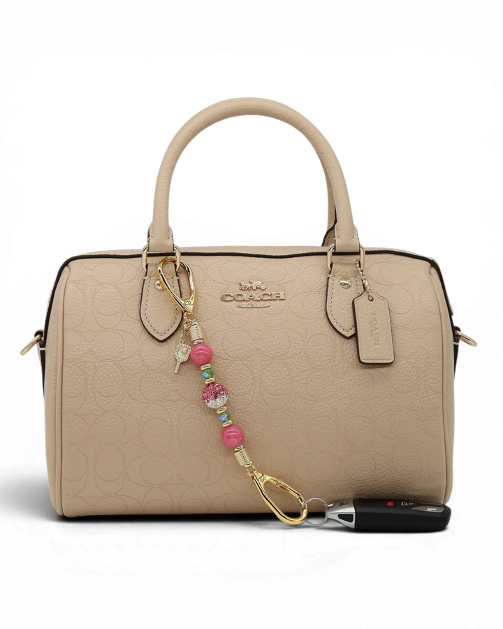 LD Keyfinder Golden Rally Mini with lime green glass, violet jade, and crystal beads on a beige designer handbag.