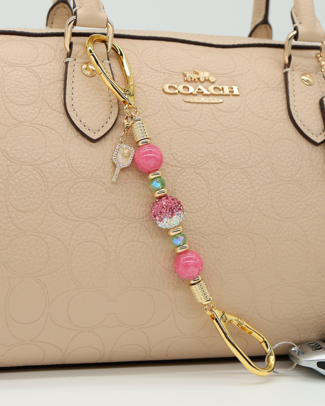 LD Keyfinder Golden Rally Mini with pink jade, lime glass beads, crystal center, and pickleball paddle charm on bag.