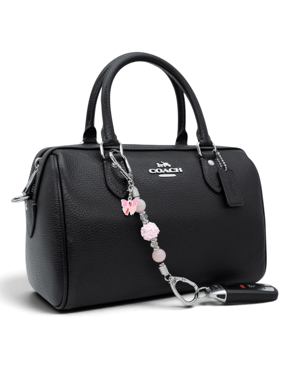 LD Keyfinder Hope Blooms-Mini attached to a black handbag, featuring rose quartz, crystal beads, and a pink ribbon charm